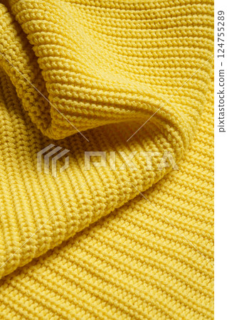 Knitted clothes. Waves of yellow fabric with a knitting pattern. Textiles. Banner for advertising goods for creativity. Knitted clothes. Waves of yellow fabric with a knitting pattern. Textiles. Banner for advertising goods for creativity. 124755289