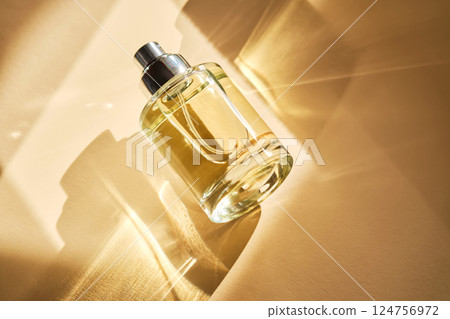 Perfume on a beige background in the rays of bright sun with beautiful highlights. 124756972