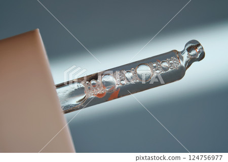 Pipette with serum on blue background with sunlight. 124756977