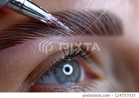 Eyebrow is being brushed with clear styling gel 124757035