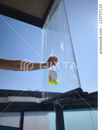 Window cleaner holding bottle and preparing to clean balcony glass panel 124757118