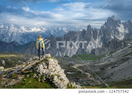 Young woman with backpack on a rock in majestic mountain valley Young woman with backpack on a rock in majestic mountain valley 124757342