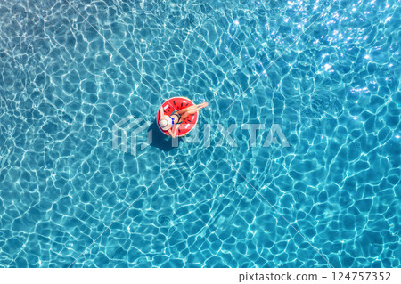 Aerial view of a woman swimming with red swim ring in blue sea 124757352