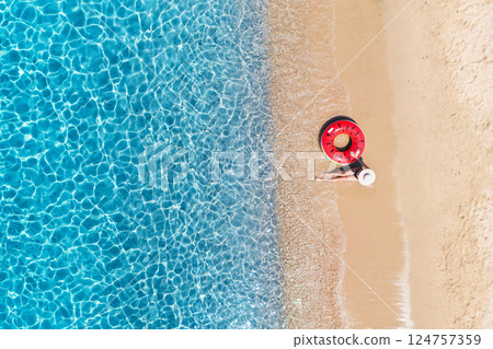 Aerial view of a woman with red swim ring on beach and sea Aerial view of a woman with red swim ring on beach and sea 124757359