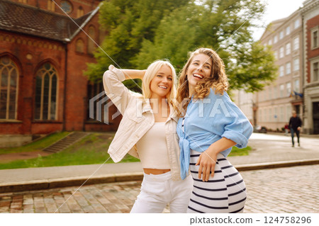 Two beautiful women are walking down the street. Fun and walking concept. Active lifestyle. 124758296