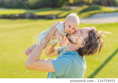 Father and newborn baby on a meadow in the park. Tender moment of bonding and love in nature. Parenthood, fatherhood, and family connection concept Father and newborn baby on a meadow in the park. Tender moment of bonding and love in nature. Parenthood, fatherhood, and family connection concept 124758453