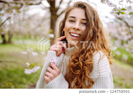Attractive woman enjoys scent of flowers in spring garden. Concept of relaxation, spring, youth. 124758501
