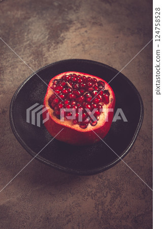 sliced fresh pomegranate, on a black plate, top view, rustic style, no people, 124758528