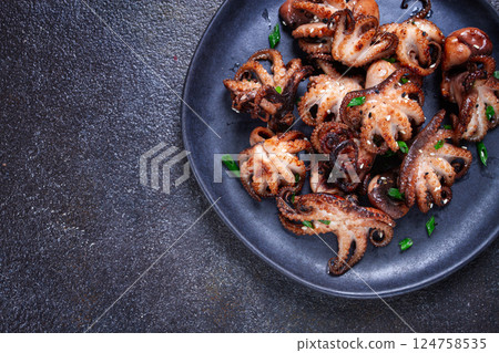 Grilled baby octopus, served with chopsticks, on a black plate, homemade, no people, 124758535