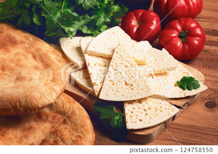 Georgian sliced cheese,on a wooden chopping board, with tomatoes with herbs and lavash, rustic style, Georgian cuisine, no people Georgian sliced cheese,on a wooden chopping board, with tomatoes with herbs and lavash, rustic style, Georgian cuisine, no people 124758550