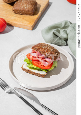 Toast club sandwich made of grain bread with prosciutto, cheese, tomatoes, lettuce and sauce  124758606