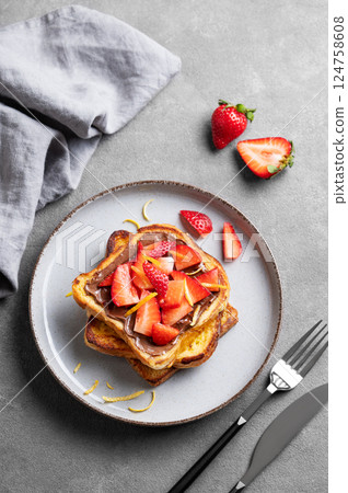 Toasted bread with chocolate cream and strawberries on a plate on a dark background Toasted bread with chocolate cream and strawberries on a plate on a dark background 124758608