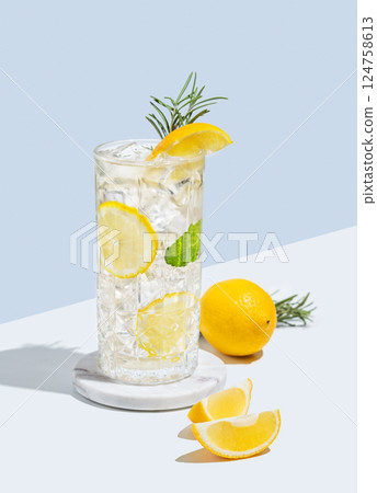 Lemonade with lemon, rosemary and ice in a glass on a white  blue background with shadow and fruits. 124758613