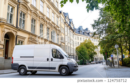 White delivery van driving on a historic cobblestone street with stylish storefronts 124758712
