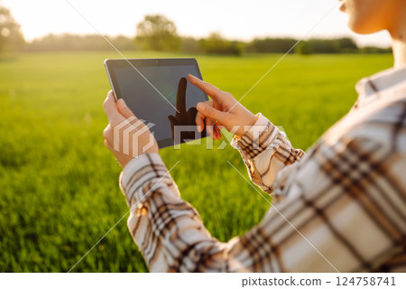 A young woman agronomist checks the growth of the crop. Concept of gardening, ecology. 124758741