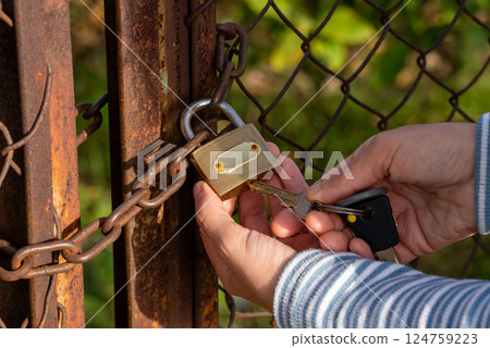 Woman hand holding key and unlocking padlock. Woman hand holding key and unlocking padlock. 124759223