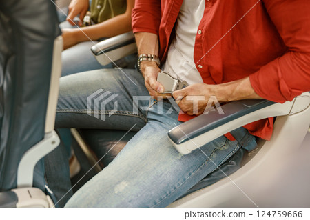 A man is seen buckling his seatbelt on an airplane as he prepares eagerly for takeoff A man is seen buckling his seatbelt on an airplane as he prepares eagerly for takeoff 124759666