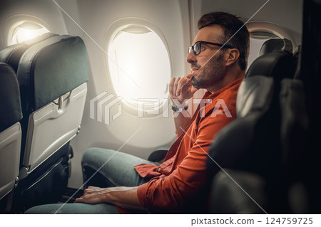 A Thoughtful Traveler on an Airplane, Engaging in Contemplation and Enjoying the Journey A Thoughtful Traveler on an Airplane, Engaging in Contemplation and Enjoying the Journey 124759725