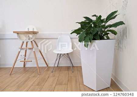 Minimalist room with white high chair, modern chair, and potted plant on wooden floor Minimalist room with white high chair, modern chair, and potted plant on wooden floor 124760348