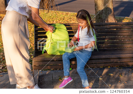 Child with green backpack on park bench at sunset Child with green backpack on park bench at sunset 124760354