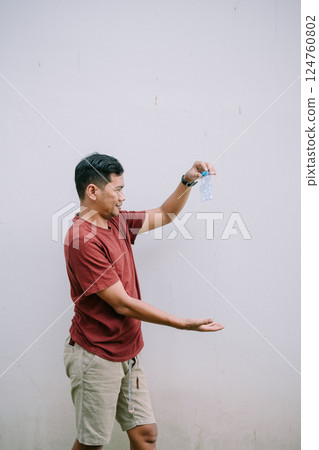 Man contemplates squashed water bottle against a clean white backdrop 124760802
