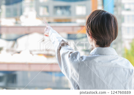 The back of a female worker pointing at a construction site 124760889