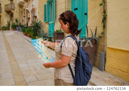 Woman tourist with a paper map and backpack exploring maltese town Birgu 124762136
