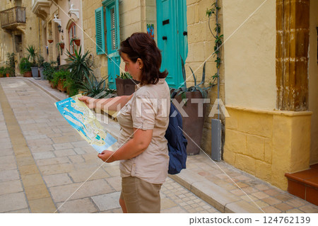 Woman tourist with a paper map and backpack exploring maltese town Birgu 124762139