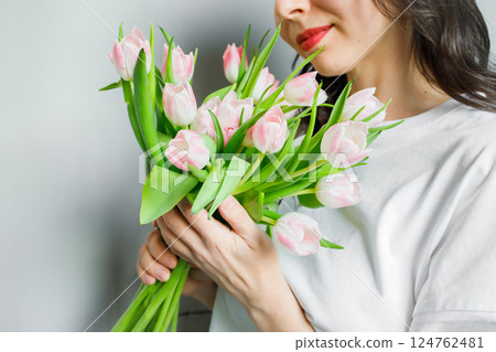 Pink tulips bouquet in hands of young woman close up Pink tulips bouquet in hands of young woman close up 124762481