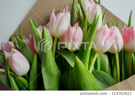 Pink tulips bouquet wrapped in brown craft paper close up Pink tulips bouquet wrapped in brown craft paper close up 124763021