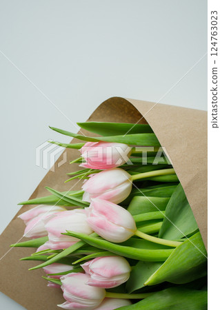 Pink tulips bouquet wrapped in brown craft paper close up Pink tulips bouquet wrapped in brown craft paper close up 124763023