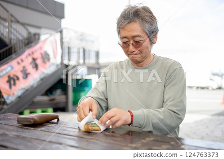 一位老人在長椅上吃飯 124763373