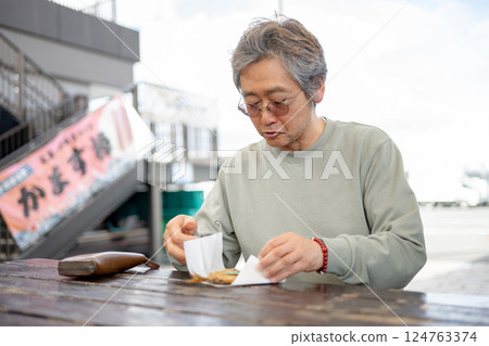 一位老人在長椅上吃飯 一位老人在長椅上吃飯 124763374