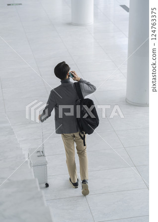 一名 40 多歲男子背著手提包和智慧型手機行走，後面視圖 124763375