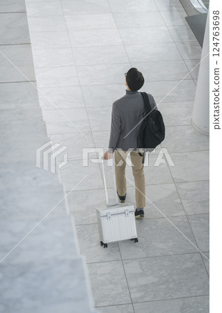 一名 40 多歲男子提著行李箱行走的背影 124763698