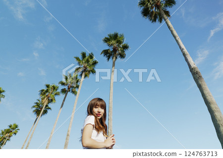 A woman enjoying a resort with palm trees in the background 124763713