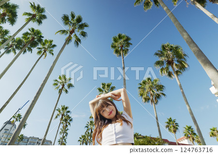 一位女士在度假村享受假期，背景是棕櫚樹 124763716
