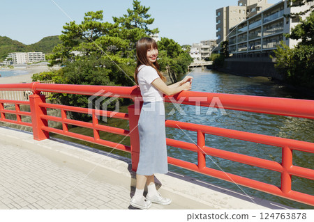 一名女子站在紅橋的欄桿上 一名女子站在紅橋的欄桿上 124763878