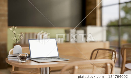 The white screen laptop, books and a coffee on wooden table with the blurred background of cosy cafe 124764092