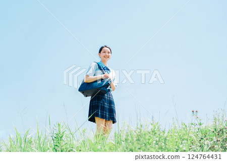 A high school girl in summer clothes walking along the riverbank 124764431