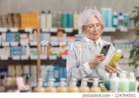 Mature woman in summer clothes scans code on medicinal shampoo to check expiration date 124764501