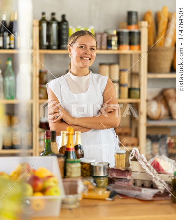 Young woman with a set of products on the background of shelves with food in a store Young woman with a set of products on the background of shelves with food in a store 124764503