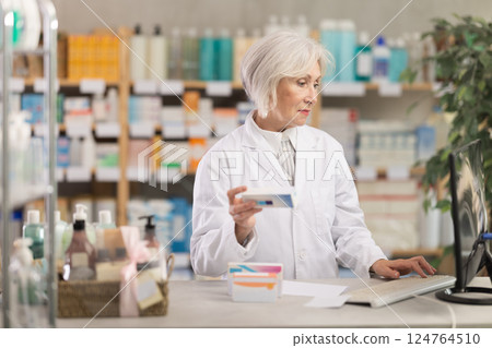 Elderly woman seller offering ointment in pharmacy Elderly woman seller offering ointment in pharmacy 124764510