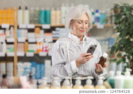 Elderly woman scanning qr code of syrup 124764528