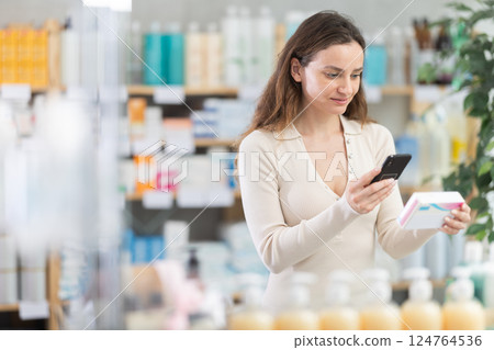 Woman in pharmacy scans QR code on pills box Woman in pharmacy scans QR code on pills box 124764536