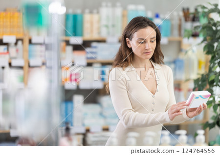 Girl in summer clothes looking for medicine in pharmacy 124764556