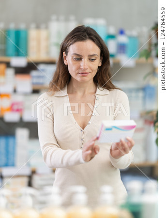 Girl in summer clothes looking for medicine in pharmacy 124764559