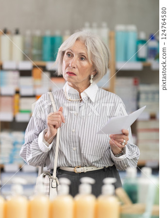 retired woman chooses medicines at a pharmacy retired woman chooses medicines at a pharmacy 124764580