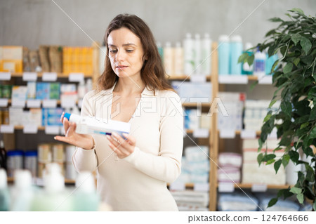 In drug store, woman examine ointment for bruises In drug store, woman examine ointment for bruises 124764666