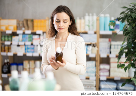 In drug store, woman examine antitussive syrup 124764675